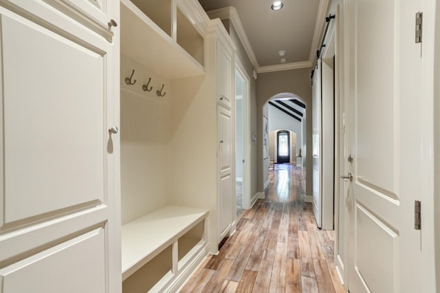 mudroom with ornamental molding, a barn door, and light hardwood / wood-style floors