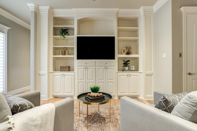 living room with decorative columns, crown molding, and light hardwood / wood-style flooring