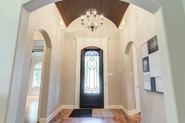 foyer featuring lofted ceiling, wood-type flooring, wooden ceiling, and a chandelier