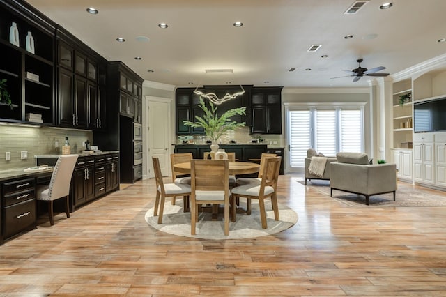 dining room with ceiling fan, ornamental molding, built in desk, and light wood-type flooring