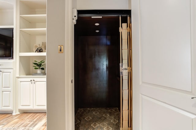 corridor with elevator and light wood-type flooring