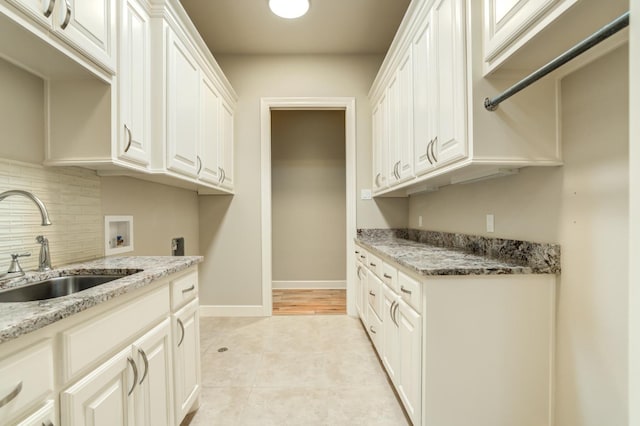 kitchen featuring tasteful backsplash, sink, white cabinets, and light stone counters