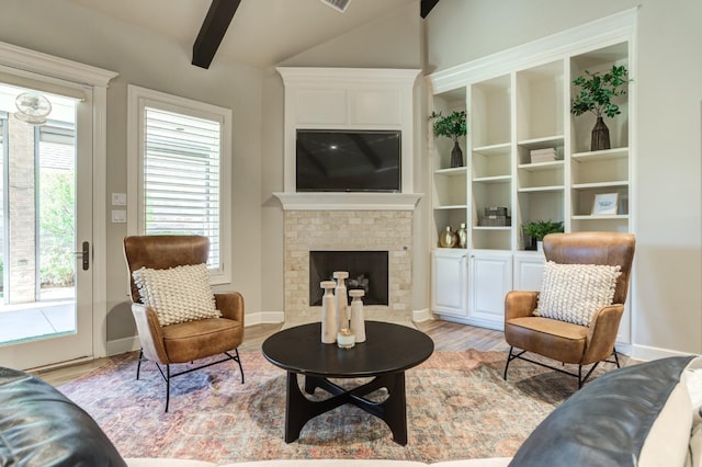 living room with light hardwood / wood-style floors, a brick fireplace, and vaulted ceiling with beams