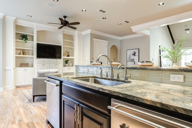 kitchen with light stone counters, sink, stainless steel dishwasher, and light wood-type flooring