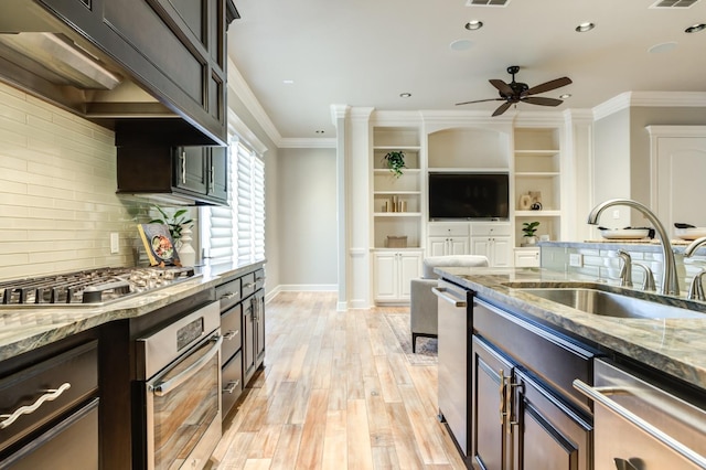 kitchen with sink, crown molding, dark brown cabinets, dark stone counters, and stainless steel appliances