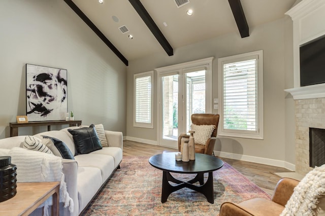 living room featuring a brick fireplace, beam ceiling, and light hardwood / wood-style floors