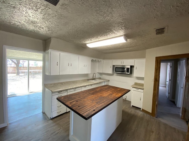 kitchen with wood counters, dark hardwood / wood-style floors, a center island, and white cabinets