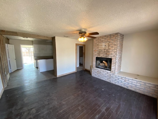 unfurnished living room featuring a brick fireplace, a textured ceiling, dark wood-type flooring, and ceiling fan