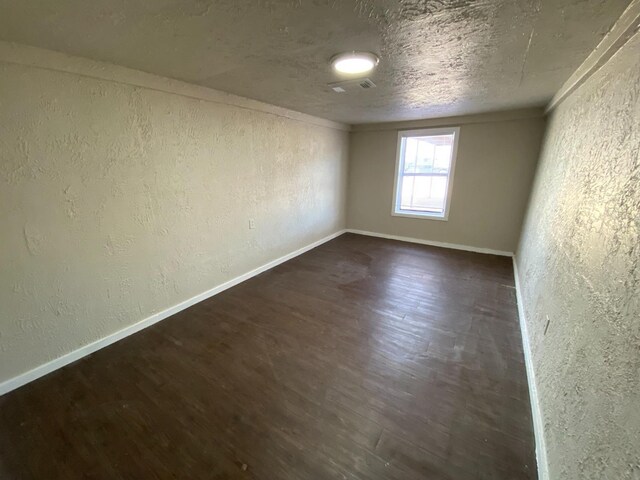 spare room featuring dark hardwood / wood-style floors and a textured ceiling