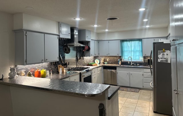 kitchen featuring appliances with stainless steel finishes, sink, backsplash, kitchen peninsula, and wall chimney range hood