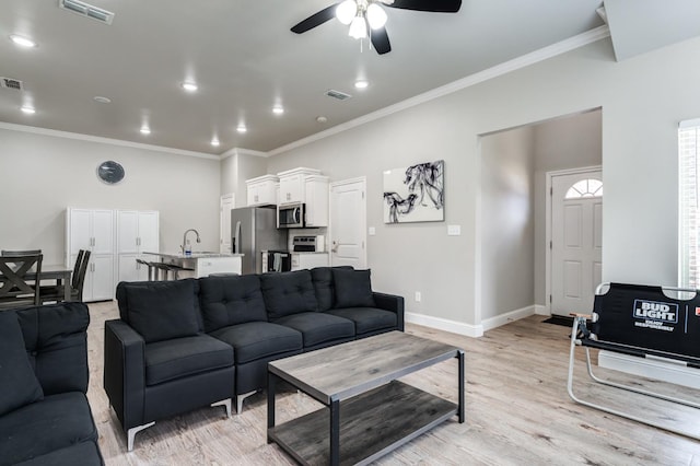 living area featuring ceiling fan, ornamental molding, light wood-style flooring, and visible vents