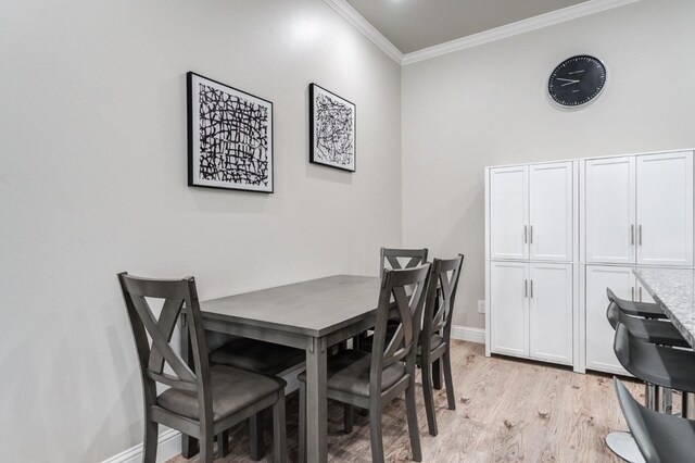 dining room with baseboards, ornamental molding, and light wood-type flooring