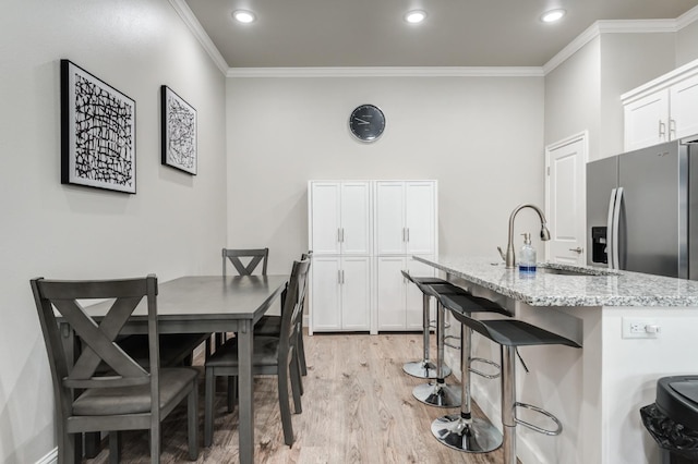 dining room featuring light wood-type flooring, ornamental molding, and recessed lighting