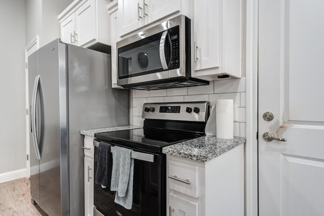 kitchen with light wood-style flooring, stainless steel appliances, white cabinets, baseboards, and tasteful backsplash