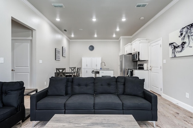 living area featuring ornamental molding, light wood finished floors, and visible vents