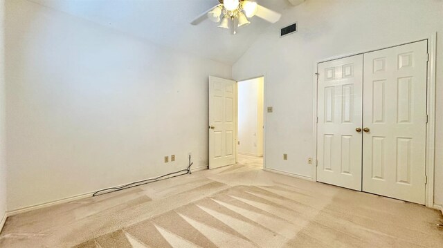 unfurnished bedroom featuring light carpet, high vaulted ceiling, a closet, and ceiling fan