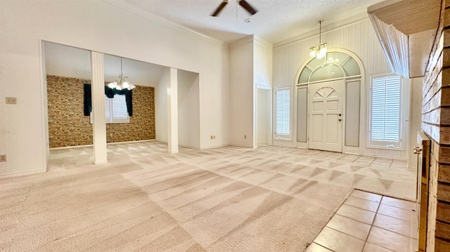 carpeted entryway featuring ornamental molding, ceiling fan with notable chandelier, and a textured ceiling