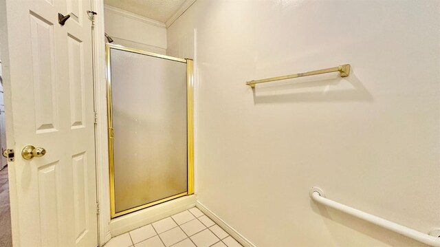 bathroom featuring a shower with door, crown molding, and tile patterned floors