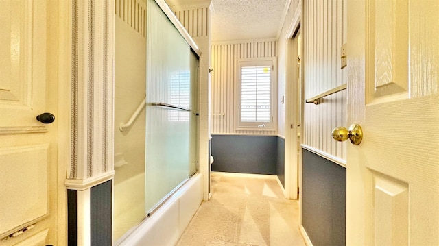 bathroom featuring shower / bath combination with glass door and a textured ceiling