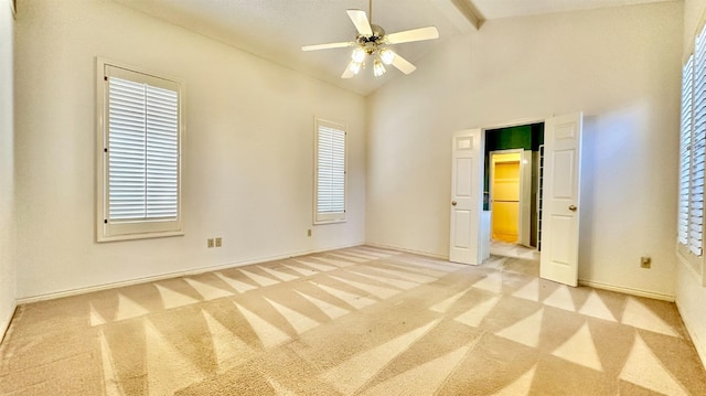 unfurnished bedroom featuring beamed ceiling, ceiling fan, light colored carpet, and high vaulted ceiling