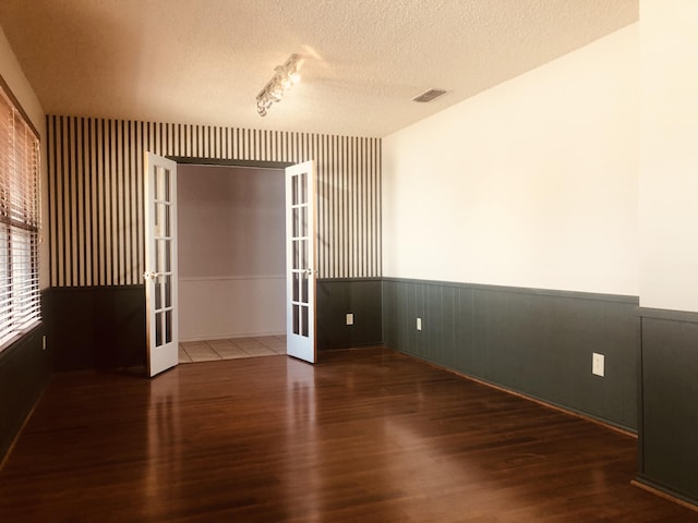 3423 94th St, Lubbock, TX 79423 - empty room with french doors, wood finished floors, wainscoting, and a textured ceiling