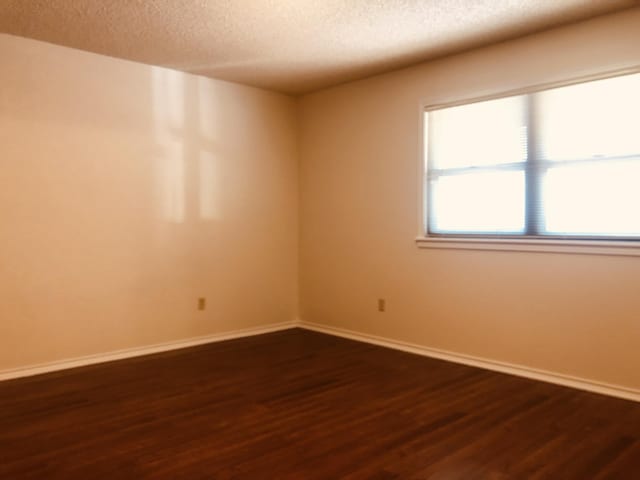3423 94th St, Lubbock, TX 79423 - spare room with a textured ceiling, dark wood-style floors, and baseboards