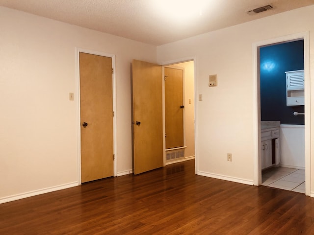 3423 94th St, Lubbock, TX 79423 - unfurnished bedroom with wood finished floors, baseboards, and connected bathroom