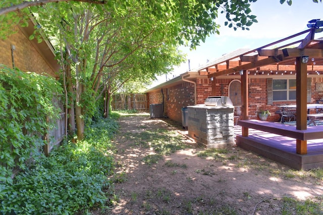 3423 94th St, Lubbock, TX 79423 - view of yard with a wooden deck, central air condition unit, a pergola, and an outdoor kitchen