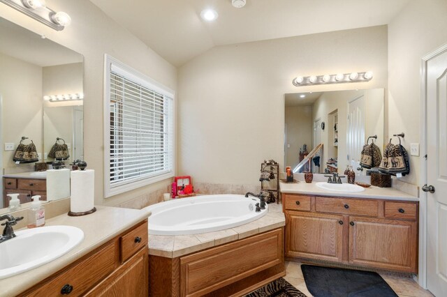 bathroom with tile patterned floors, lofted ceiling, vanity, and a tub