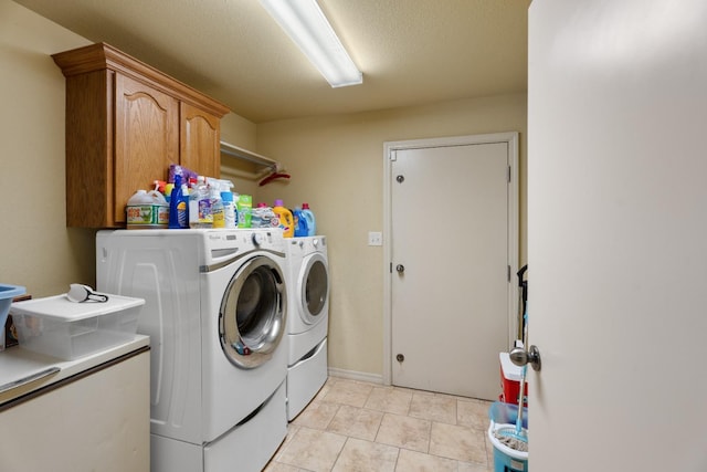 laundry area featuring washing machine and dryer, cabinets, a textured ceiling, and light tile patterned flooring