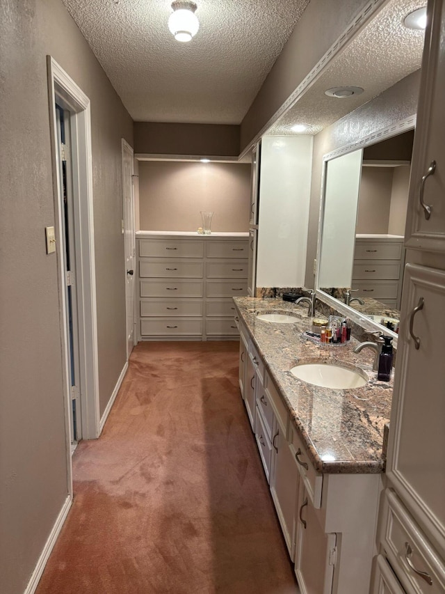 3004 80th St, Lubbock, TX 79423 - bathroom featuring a textured ceiling, double vanity, and baseboards