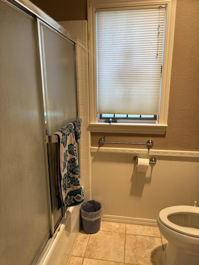 3004 80th St, Lubbock, TX 79423 - full bathroom featuring a decorative wall, toilet, wainscoting, bath / shower combo with glass door, and tile patterned floors