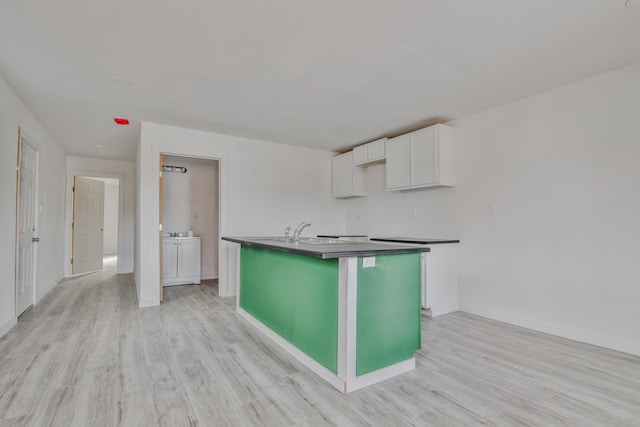 kitchen with light wood-type flooring, sink, an island with sink, and white cabinets