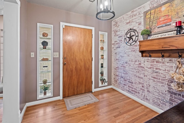 foyer featuring brick wall and light hardwood / wood-style floors