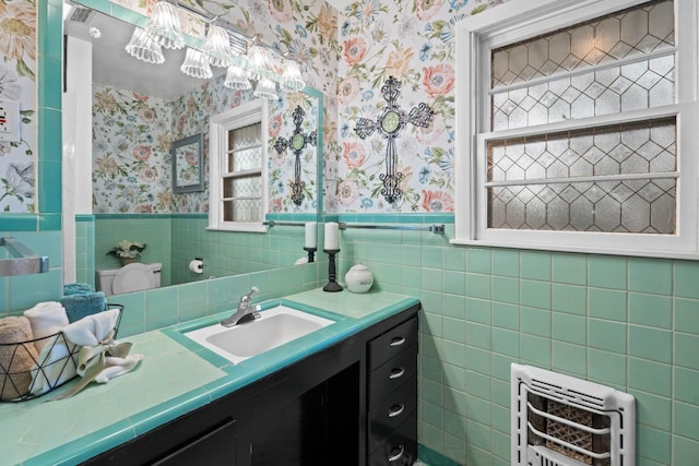 bathroom featuring vanity, heating unit, and tile walls