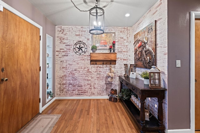 foyer featuring brick wall and light wood-type flooring