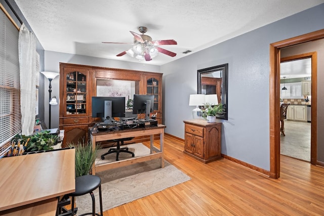 office area featuring ceiling fan, light hardwood / wood-style flooring, and a textured ceiling