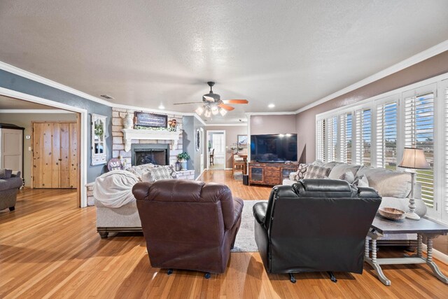 living room with crown molding, a fireplace, a textured ceiling, and light wood-type flooring