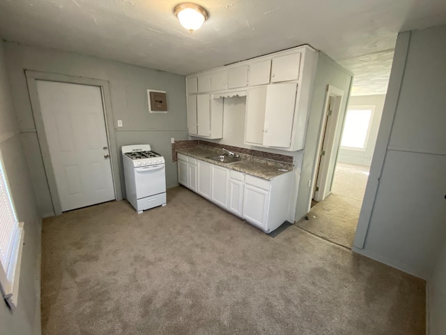 kitchen featuring sink, white cabinetry, electric panel, light colored carpet, and white gas stove