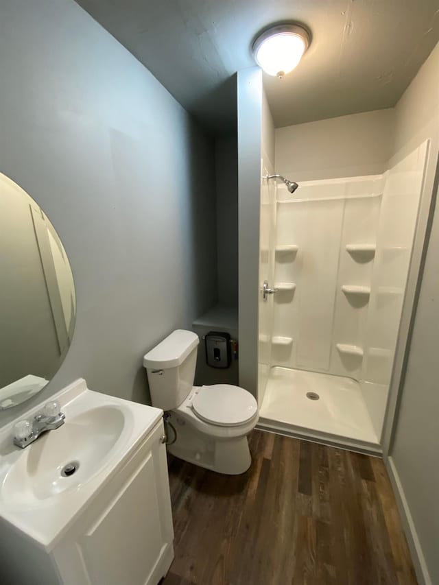 bathroom featuring wood-type flooring, toilet, vanity, and a shower