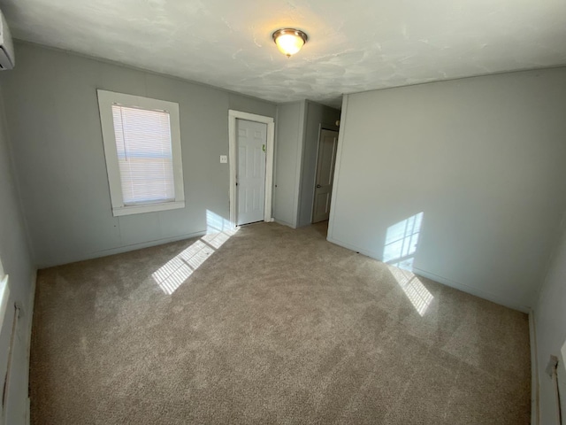 spare room featuring a wall mounted AC and light carpet