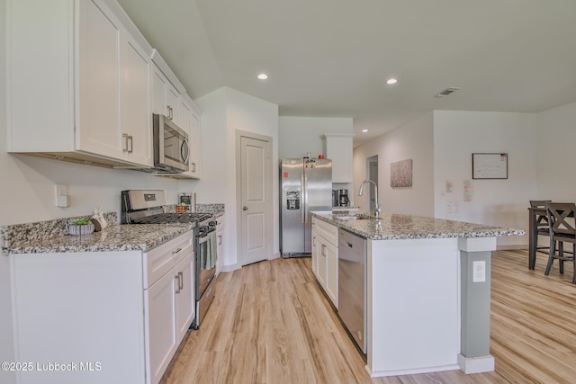 7406 9th St, Lubbock, TX 79416 - kitchen featuring stainless steel appliances, a sink, light wood-style floors, an island with sink, and white cabinetry