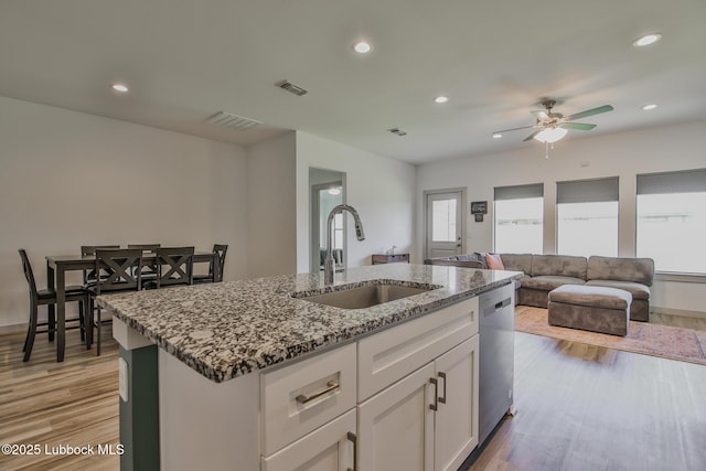 7406 9th St, Lubbock, TX 79416 - kitchen featuring a sink, dishwasher, a ceiling fan, an island with sink, and light stone counters