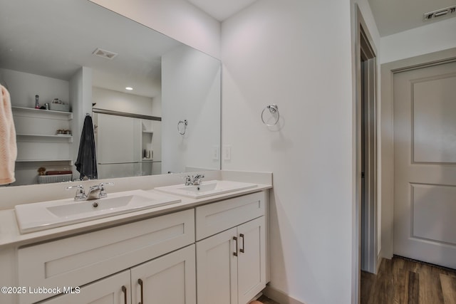 7406 9th St, Lubbock, TX 79416 - bathroom featuring double vanity, wood finished floors, baseboards, and recessed lighting