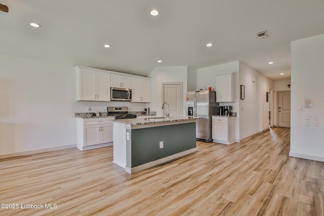 7406 9th St, Lubbock, TX 79416 - kitchen with stainless steel appliances, white cabinets, light wood-style floors, and recessed lighting