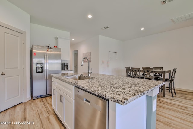 7406 9th St, Lubbock, TX 79416 - kitchen with stainless steel appliances, a sink, light wood finished floors, white cabinetry, and recessed lighting