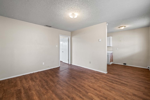 unfurnished room with dark wood-type flooring and a textured ceiling