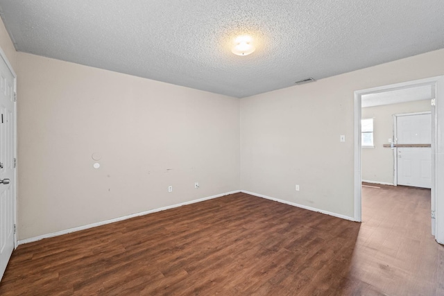 empty room featuring dark hardwood / wood-style flooring and a textured ceiling