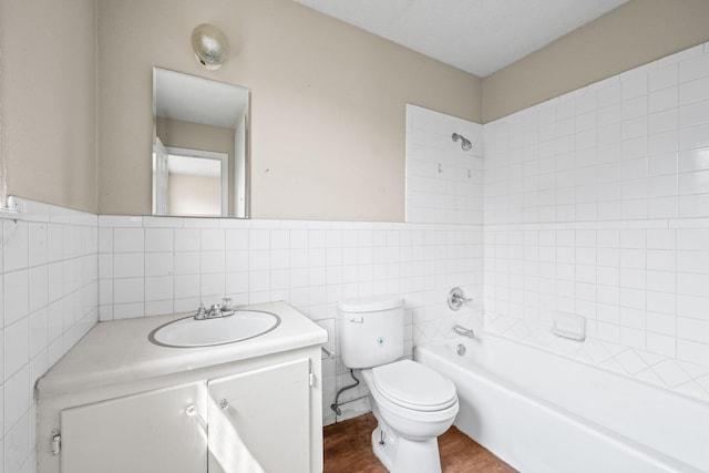 full bathroom featuring toilet, wood-type flooring, tile walls, vanity, and tiled shower / bath combo