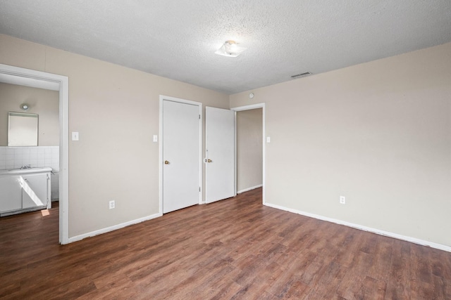 unfurnished bedroom with dark hardwood / wood-style flooring, sink, and a textured ceiling